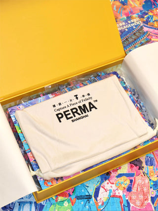 A yellow box containing a fabric pouch labeled PERMA SHANGHAI placed on top of colorful puzzle pieces.