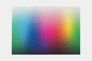A completed jigsaw puzzle displaying a smooth gradient transitioning through multiple colors, including blue, green, pink, yellow, and orange.