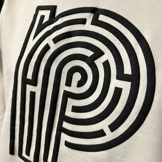 Black maze-like circular design with thick lines printed on a light-colored fabric background.