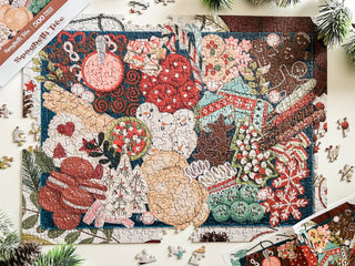 A completed jigsaw puzzle on a table depicts assorted holiday cookies and decorations, surrounded by a few unplaced pieces and pine branches.
