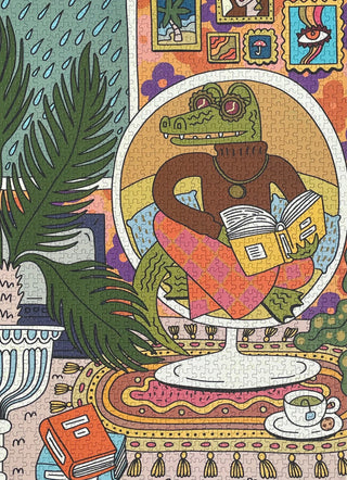 Illustrated jigsaw puzzle showing an alligator wearing a sweater and pants, sitting on a chair reading a book in a colorful, cozy room with plants, books, and a cup of tea.