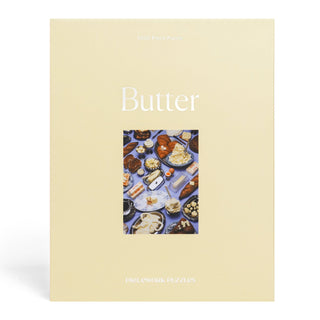 The Butter | 1,000 Piece Jigsaw Puzzle by Piecework Puzzles comes in a beige box labeled "Butter," showcasing high-quality buttery dish art at the center and indicating it's a 1,000-piece puzzle.