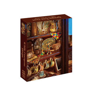The While Everyone Sleeps 1,000 Piece Jigsaw Puzzle box, crafted from recycled paper, depicts a wooden hutch filled with various ceramic plates, mugs, and two toy soldiers.