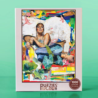The Ramona Leeza 1,000 piece jigsaw puzzle box, featuring a Noland Anderson abstract impressionist portrait of a woman lounging in a chair surrounded by tropical foliage.