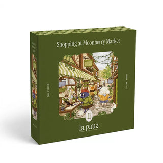 La pauz Shopping At Moonberry Market is a 500-piece jigsaw puzzle featuring a charming, illustrated market scene with animal characters by Hanna Wainio, packaged in a green box.