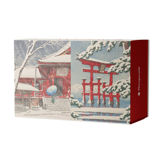 The Kawase Hasui: Snowfall | 120 Piece Double-Sided Jigsaw Puzzle Set by Pomegranate comes in a rectangular box adorned with Japanese temple and torii gate illustrations set in a snowy landscape, featuring primarily red, white, and blue tones, and accented by a red side panel with white text.