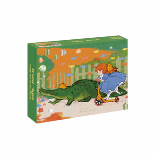 A girl in a blue dress rides a scooter alongside a large green alligator wearing a hat, with vibrant fish and plants in the background, featured on the box art of the WEVE Wani-Kun 500 Piece Jigsaw Puzzle—expertly crafted from premium blue board for a velvet-like soft touch.