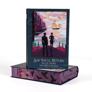 A Say You’ll Return 250 Piece Jigsaw Puzzle box shaped like a book, featuring a silhouette of two people on a dock overlooking a harbor and a puzzle base with flying crows.