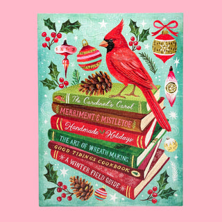 Holiday Bookclub by WerkShoppe is a festive 500-piece puzzle featuring a red cardinal perched on holiday books with ornaments, holly, pinecones, and berries against a teal background—perfect for cozy winter days.