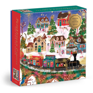 Box of the Joy Laforme Twinkletown Express 1,000 Piece Jigsaw Puzzle by Chronicle Books, featuring a vibrant holiday village scene with decorated houses, Christmas trees, and the festive Twinkletown Express train traveling through a snowy landscape.