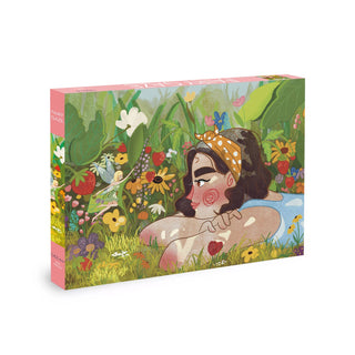 The Fairy Gaze 500 Piece Jigsaw Puzzle by Olleo Puzzles features an illustrated woman with a yellow headband resting in a vibrant garden filled with colorful flowers, strawberries, and lush greenery.
