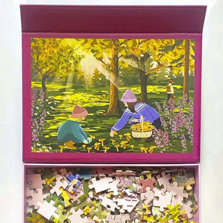 ViSSEVASSE’s “Chanterelles” 300 Piece Jigsaw Puzzle features a captivating illustration of two people foraging for chanterelles in a sun-dappled autumn forest. Ideal for nature enthusiasts, this enchanting puzzle captures the warm spirit of fall, with scattered pieces inviting you to piece together the vibrant scene.