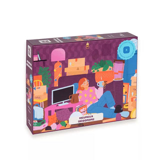 The Heureux Désordre 500 Piece Jigsaw Puzzle by Heol Editions features a vibrant illustration of a relaxed person in a cluttered room with boxes, plants, and a cat, capturing charming details from this French artist.