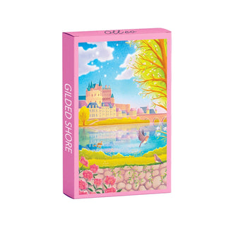 The Gilded Shore | 99 Piece Jigsaw Puzzle by Olleo Puzzles showcases a vibrant lakeside town inspired by Loire castles, with a castle, flowers, trees, and birds on the illustrated box.
