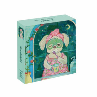 The Goodnight | 208 Piece Jigsaw Puzzle by WEVE features a dreamy illustration of a sleepy green dog in a pink dress sipping from a mug at night, set against a background with a window, roses, and a crescent moon. Crafted from recycled paper, this pastel puzzle box is perfect for cozy evenings.