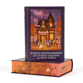 This enchanting keepsake box from Kingdom of Threads is shaped like a book and features Nicole Gustafsson’s captivating artwork of the Slightly Haunted Bookshop, illuminated at night and surrounded by friendly ghosts. The box reads, “Slightly Haunted Bookshop | 250 Piece Jigsaw Puzzle” and includes a 250-piece puzzle for hours of whimsical fun.