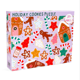 The Holiday Cookies | 500 Piece Jigsaw Puzzle by Callie Danielle features festive cookie illustrations—gingerbread houses, stars, trees, snowflakes, and candy canes—on a light purple background. A perfect Christmas gift for puzzle lovers.