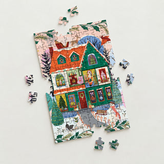 A partially assembled Home For the Holidays 150 Piece Jigsaw Puzzle by Spaghetti Tree depicting a festive two-story house with decorations and a snowman, surrounded by several loose pieces.