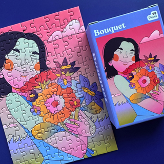 A Bouquet | 99 Piece Jigsaw Puzzle box next to its completed puzzle, both featuring an illustration of a smiling person holding a colorful bouquet of flowers.