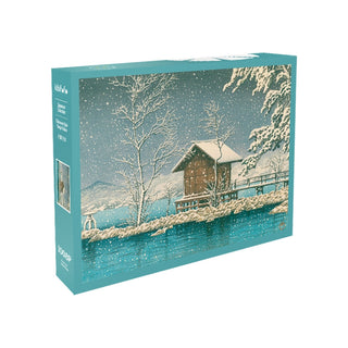 The Kibifufu Chitazawa Lake Hanju Palace 1,008 Piece Jigsaw Puzzle features winter art of a snowy landscape with a cabin, trees, and a fence by a river.