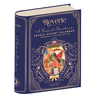 A dark blue box shaped like a book, Reverie Puzzles’ A Bookish Christmas Puzzle Advent Calendar | 24 x 99 Piece Jigsaw Puzzles, features mini puzzles and an illustrated woman reading by a window.