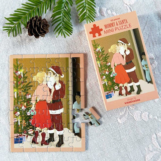 The ViSSEVASSE "Mommy & Santa" 42 Piece Jigsaw Puzzle features a heartwarming scene of a woman hugging Santa Claus near a decorated Christmas tree, as a child peeks from behind. Surrounded by pinecones and fabric, this charming mini puzzle is ideal for travel or cozy holiday get-togethers.