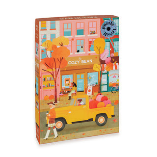 The Trevell “Fall in NYC” 500 piece jigsaw puzzle features a charming autumn scene with a yellow truck filled with pumpkins, people enjoying time outside The Cozy Bean café, and vibrant fall foliage set against colorful city buildings. This eco-friendly puzzle is thoughtfully packaged in a reusable cotton bag for convenient storage and perfect gifting.