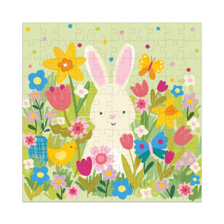 The Bunny in Flowers 100 Piece Jigsaw Puzzle by My Mind’s Eye features a white bunny with pink ears among colorful flowers and butterflies in a green field—perfect for kids who love puzzles.
