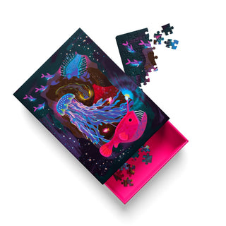 The Deep Sea | 99 Piece Jigsaw Puzzle by Ohh Deer features vibrant neon sea creatures and deep sea animals on its box, with some pieces assembled and others scattered, all shown partially opened against a white background.
