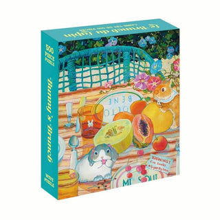The WEVE Bunny's Brunch 500 piece jigsaw puzzle is made from recycled paper and premium blue board, showcasing a vibrant picnic scene with fruit, a guinea pig, a hamster, and brunch items on the table.
