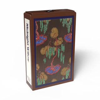 A brown rectangular box labeled “Midnight Willow” from Penny Puzzle, featuring a decorative illustration of willow trees on the front panel, captures the vintage charm of a 99-piece mini jigsaw puzzle and draws inspiration from Art Deco puzzle designs reminiscent of E. A. Séguy’s artistic style.