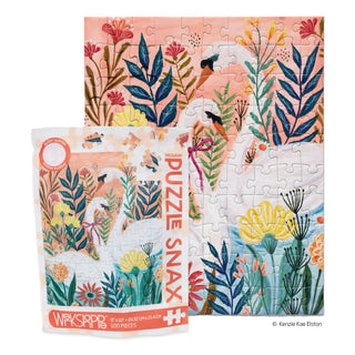 The Serene Swans | 100 Piece Jigsaw Puzzle by WerkShoppe is shown completed with its box, both featuring vibrant floral art and glittery accents.