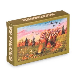 Here is a rewritten sentence using the provided product data: The Trevell "November | 99 Piece Jigsaw Puzzle" features a vividly illustrated autumn scene with people, a campfire, trees, a cabin, and birds set in a colorful landscape. Made in Turkey, this puzzle box captures the vibrant essence of fall.