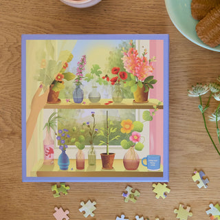 The ViSSEVASSE "Plants & Me" 500 piece jigsaw puzzle features a lively illustration of flowers in vases, scattered puzzle pieces, and a plate of pastries—ideal for plant lovers and puzzle fans.