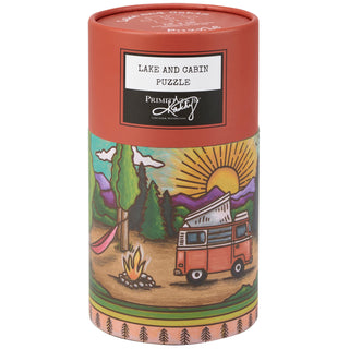 The Primitives by Kathy Lake & Cabin | 500 Piece Jigsaw Puzzle features a colorful sunset scene with van, campfire, hammock, and mountains—ideal for nature lovers.