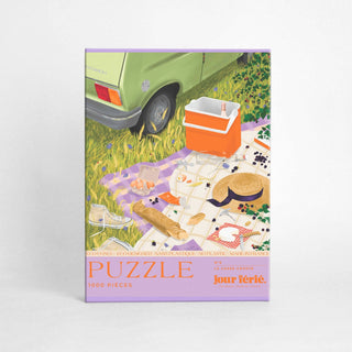 Le casse-croûte by Jour Férié is a 1,000-piece jigsaw puzzle made in France, showing a picnic scene with a green car, blanket, picnic items, and an orange cooler.