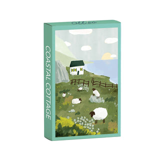 Experience the tranquil beauty of the Scottish countryside with the “Coastal Cottage | 99 Piece Jigsaw Puzzle” by Olleo Puzzles, featuring a delightful illustration of sheep grazing on grass near a white cottage by the sea, complete with a fence and dramatic cliffs in the background. The box proudly displays “Coastal Cottage,” capturing serene coastal charm in every piece.