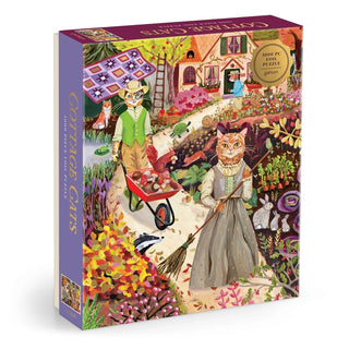Colorful puzzle box featuring an illustrated garden scene by Anja Riebensahm, with two anthropomorphic cats in vintage attire among flowers and a cottage. The box label reads Galison Cottage Cats | 1,000 Piece Jigsaw Puzzle.