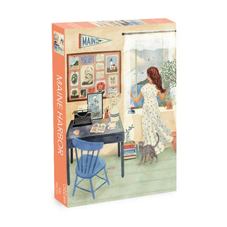 The Maine Harbor 500 Piece Jigsaw Puzzle by Olleo Puzzles features an illustration of a woman in a dress by a desk and window, with a cat, plants, and Maine-themed accents in a cozy room.