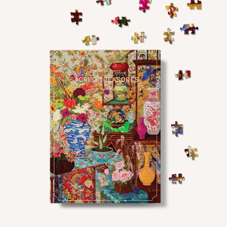 The Puzzle Theory’s Sacred Treasures | 1,000 Piece Jigsaw Puzzle box showcases vivid John Powell artwork of flowers, vases, and ornate objects, with loose puzzle pieces displayed around this premium set.