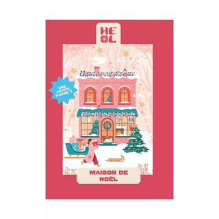 Festive house with Christmas decor, woman carrying gifts, and a decorated tree; text reads Maison de Noël. Heol Editions’ Maison de Noël | 99 Piece Jigsaw Puzzle is made in France—perfect for holiday fun!.