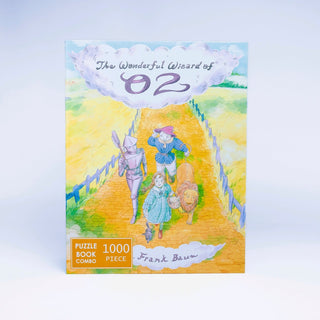 Book cover of The Wonderful Wizard of Oz featuring Dorothy, Tin Man, Scarecrow, and Lion on the yellow brick road; presented as a 1,000 piece jigsaw puzzle by Bookworm Puzzles—a perfect literary gift for any Wizard of Oz fan and puzzle enthusiast.