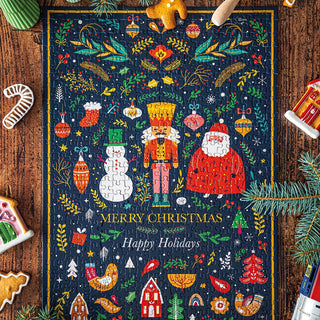 Completed the Maison Joliette "Nutcracker" 500 piece jigsaw puzzle on a wooden table, surrounded by decorated cookies and pine branches. The puzzle features festive nutcracker illustrations and holiday greetings.