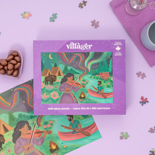 The Dancing Sky 1,000 Piece Jigsaw Puzzle by Villager Puzzles features Véro Filion’s art of a woman playing violin by a campfire with a canoe, bear, and northern lights—a celebration of Métis culture.