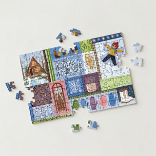 An incomplete Winter Wonderland | 150 Piece Jigsaw Puzzle by Spaghetti Tree, featuring scenes of a cabin, a child making a snow angel, mittens, and the words Winter Wonderland.