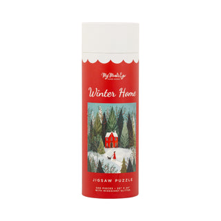 A cylindrical red box labeled “Winter Home | 500 Piece Jigsaw Puzzle” by My Mind’s Eye features an illustration of a house in snowy woods with delicate glitter accents and contains a 500-piece jigsaw puzzle.