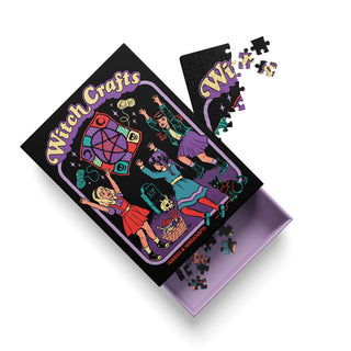 A partially completed Witch Craft | 99 Piece Jigsaw Puzzle by Ohh Deer displays three girls in witch costumes and a cat on the cover, featuring quirky Steven Rhodes artwork. Puzzle pieces are scattered around the open box.