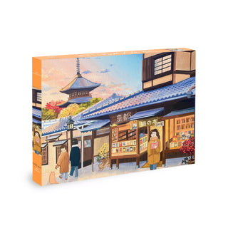 Discover The Bookseller | 500 Piece Jigsaw Puzzle by Olleo Puzzles, featuring an illustrated Japanese street scene inspired by Kyoto’s Gion district. This beautifully designed puzzle captures people strolling past vibrant shops, autumn trees, and a pagoda in the background—perfect for fans of traditional Japanese art.