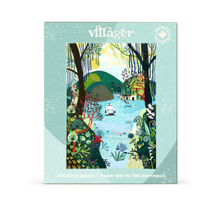 The Bowen Island 500 Piece Jigsaw Puzzle by Villager Puzzles features an illustrated lake scene with trees, mountains, and cottages, beautifully capturing the charm of a Canadian landscape. The box includes text in English and French and is bordered in a light blue-green shade.