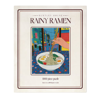 Rainy Ramen | 1,000 Piece Jigsaw Puzzle box featuring a Camille Collins illustration of chopsticks lifting noodles from a ramen bowl in a rainy city street scene.